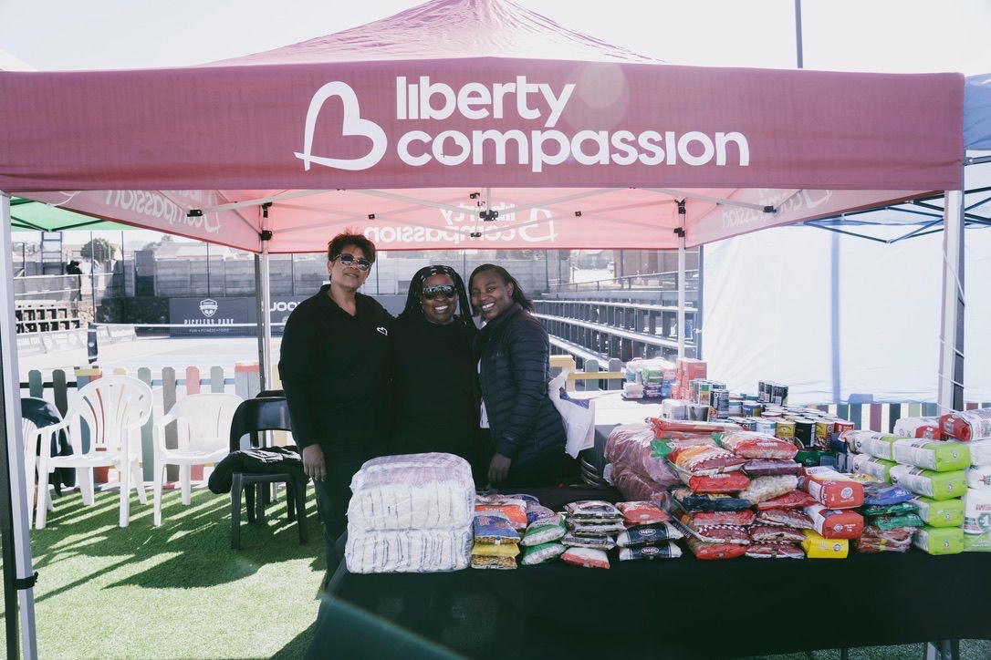 Liberty Compassion team members at the branded stand with donated groceries
