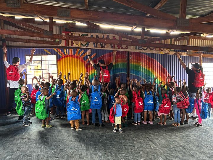 Pre-school children holding up new backpacks