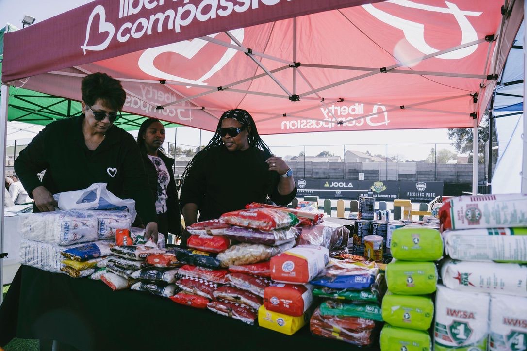 Volunteers behind a table of groceries under the Liberty Compassion gazebo